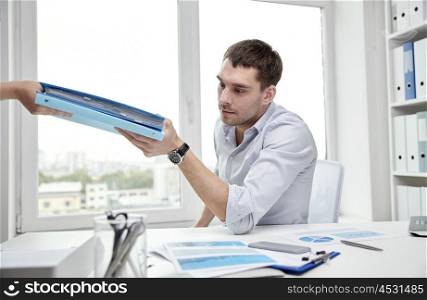 business, people and paperwork concept - businessman taking folder with papers from secretary in office