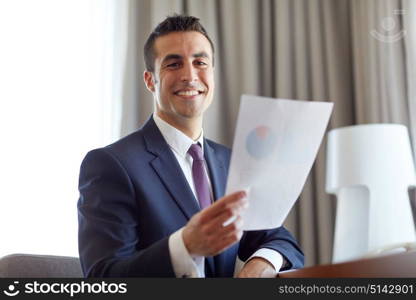 business, people and paperwork concept - businessman with papers working at hotel room. businessman with papers working at hotel room