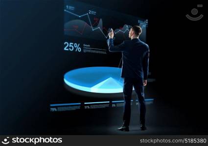 business, people and statistics concept - businessman in suit working with virtual pie chart hologram over black background. businessman working with virtual chart hologram