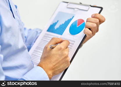 business, people and statistics concept - close up of businessman&rsquo;s hands holding pen and clipboard with charts. hands of businessman holding clipboard with charts