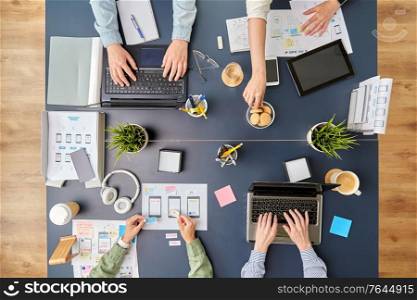 business, people and team work concept - team of startuppers with gadgets and papers working at office table. business team with gadgets working at office table