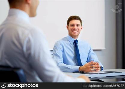 business, people and teamwork concept - happy male coworkers meeting and talking at office. happy coworkers meeting and talking at office