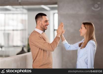 business, people and teamwork concept - happy smiling businesswoman and businessman making high five at office. man and woman making high five at office