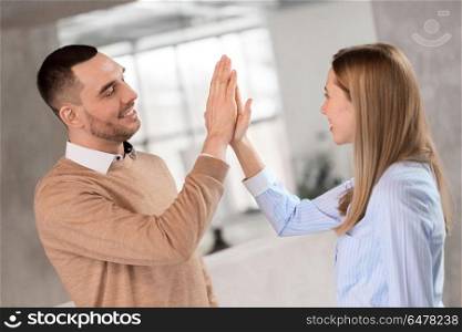 business, people and teamwork concept - happy smiling businesswoman and businessman making high five at office. man and woman making high five at office. man and woman making high five at office