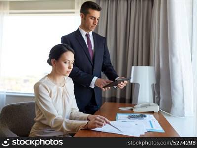business, people and teamwork concept - man and woman with papers and tablet pc computer working at hotel room. business team with papers working at hotel room