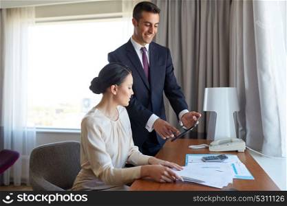 business, people and teamwork concept - man and woman with papers and tablet pc computer working at hotel room. business team with papers working at hotel room