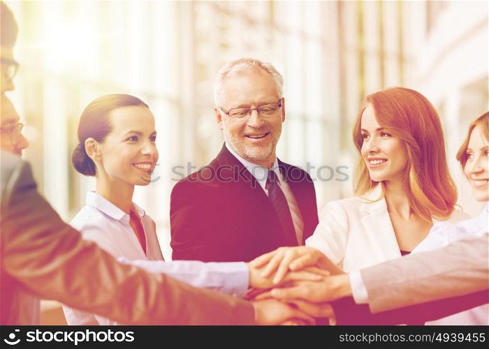 business, people and teamwork concept - smiling business people putting hands on top of each other in office. business people putting hands on top in office
