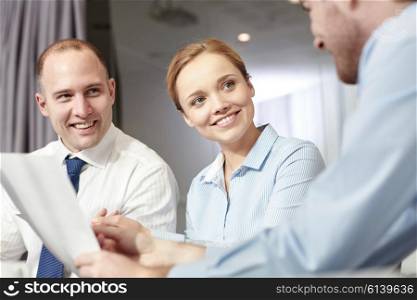 business, people and teamwork concept - smiling business team with papers meeting and talking in office