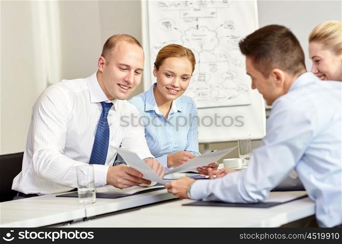 business, people and teamwork concept - smiling business team with papers meeting in office