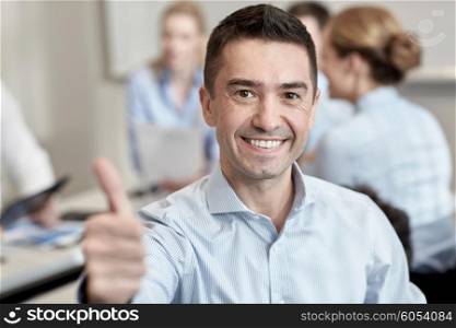 business, people and teamwork concept - smiling businessman showing thumbs up with group of businesspeople meeting in office