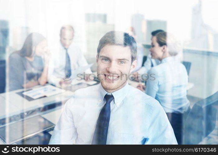 business, people and teamwork concept - smiling businessman with group of businesspeople meeting in office