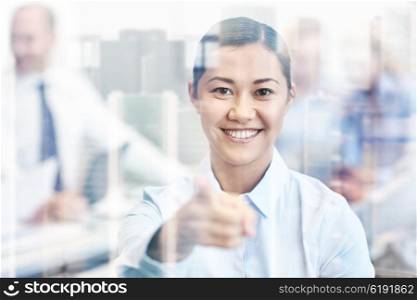 business, people and teamwork concept - smiling businesswoman pointing finger at you with group of businesspeople meeting in office