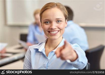 business, people and teamwork concept - smiling businesswoman pointing finger on you with group of businesspeople meeting in office