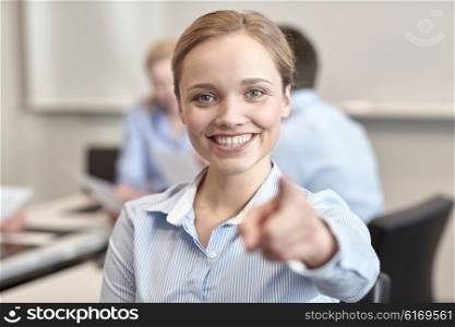 business, people and teamwork concept - smiling businesswoman pointing finger on you with group of businesspeople meeting in office