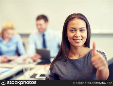 business, people and teamwork concept - smiling businesswoman showing thumbs up with group of businesspeople meeting in office