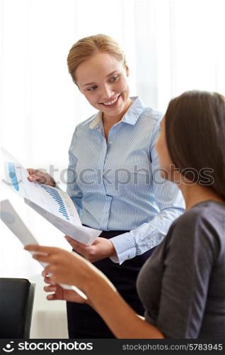 business, people and teamwork concept - smiling businesswomen with papers talking in office