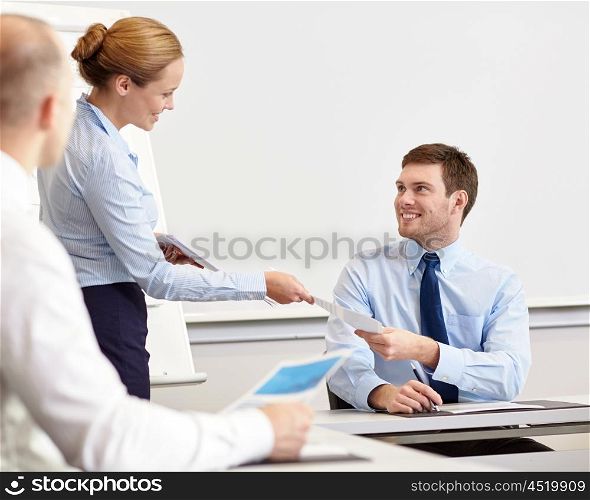 business, people and teamwork concept - smiling woman giving papers to man in office