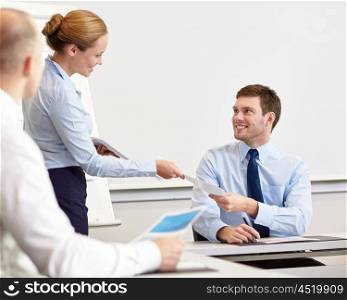 business, people and teamwork concept - smiling woman giving papers to man in office