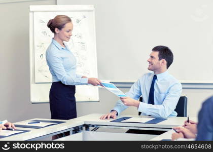 business, people and teamwork concept - smiling woman giving papers to man in office