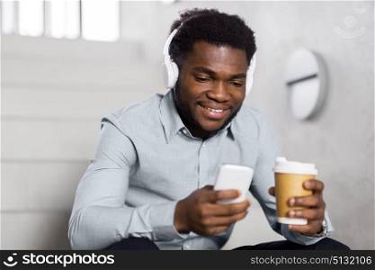 business, people and technology concept - african american businessman with headphones and smartphone listening to music at office coffee break. businessman with headphones and smartphone. businessman with headphones and smartphone