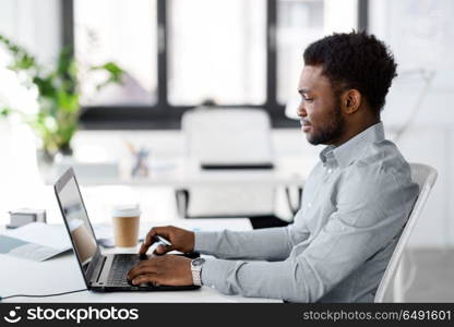 business, people and technology concept - african american businessman with laptop computer working at office. african american businessman with laptop at office. african american businessman with laptop at office