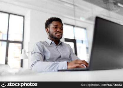 business, people and technology concept - african american businessman with laptop computer working at office. african american businessman with laptop at office. african american businessman with laptop at office
