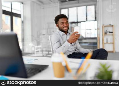 business, people and technology concept - african american businessman with smartphone at office. businessman with smartphone at office