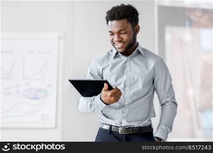 business, people and technology concept - african american businessman with tablet pc computer at office. smiling businessman with tablet pc at office. smiling businessman with tablet pc at office