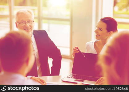 business, people and technology concept - business team with laptop computer meeting in office. business people with laptop meeting in office