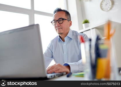 business, people and technology concept - businessman in eyeglasses with laptop computer office. businessman in eyeglasses with laptop office