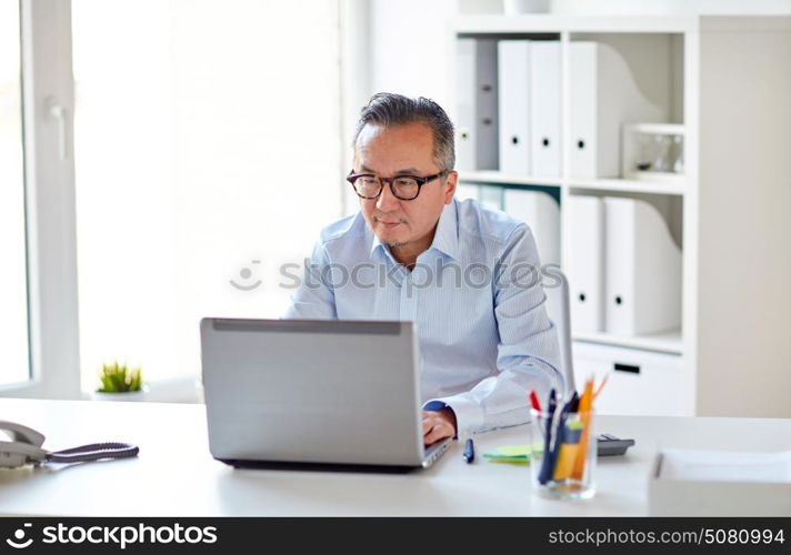 business, people and technology concept - businessman in eyeglasses with laptop computer office. businessman in eyeglasses with laptop office