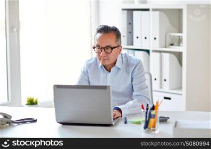 business, people and technology concept - businessman in eyeglasses with laptop computer office. businessman in eyeglasses with laptop office