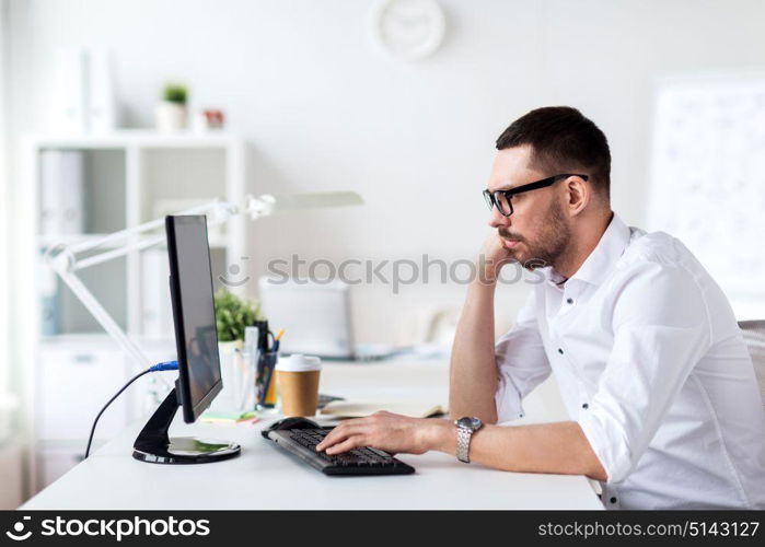 business, people and technology concept - businessman in glasses typing on computer keyboard at office. businessman typing on computer keyboard at office