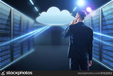 business, people and technology concept - businessman in suit looking at virtual cloud hologram over server room background. businessman looking at virtual cloud hologram