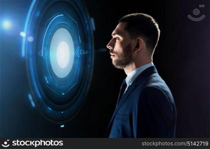 business, people and technology concept - businessman in suit looking at virtual projection over black background. businessman looking at virtual projection