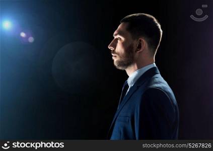 business, people and technology concept - businessman in suit over black background with lens flare. businessman over black background with lens flare