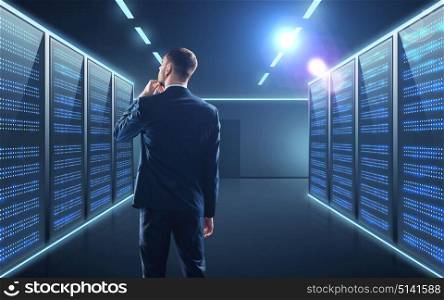 business, people and technology concept - businessman in suit over server room background. businessman over server room background