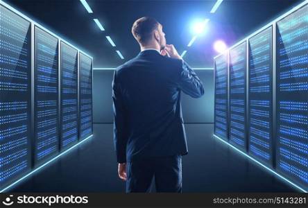 business, people and technology concept - businessman in suit over server room background. businessman over server room background