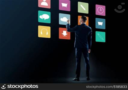 business, people and technology concept - businessman in suit touching virtual menu icons over black background. businessman in suit touching virtual menu icons