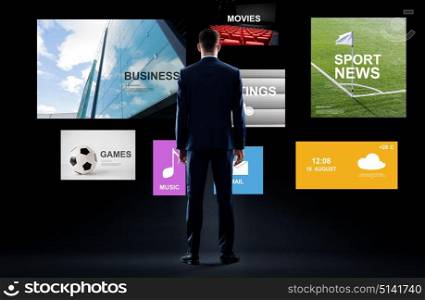 business, people and technology concept - businessman in suit with virtual applications over black background. businessman with virtual applications