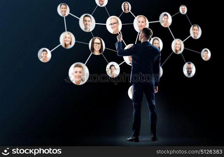 business, people and technology concept - businessman in suit with virtual icons of corporate network over black background. businessman with virtual corporate network