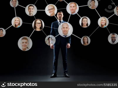 business, people and technology concept - businessman in suit with virtual icons of corporate network over black background. businessman with virtual corporate network