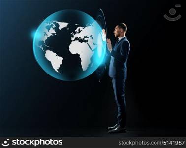business, people and technology concept - businessman in suit working with virtual earth projection over black background. businessman in suit with virtual earth projection