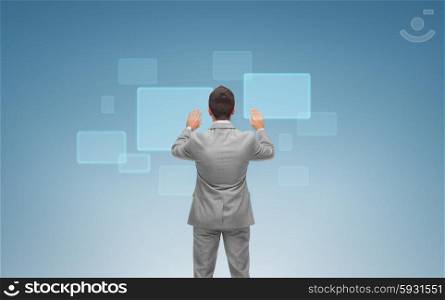 business, people and technology concept - businessman touching virtual screens over blue background from back