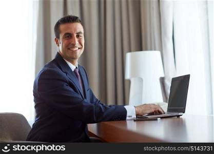business, people and technology concept - businessman typing on laptop at hotel room. businessman typing on laptop at hotel room