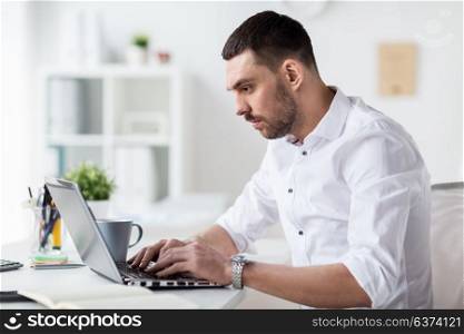 business, people and technology concept - businessman typing on laptop at office. businessman typing on laptop at office
