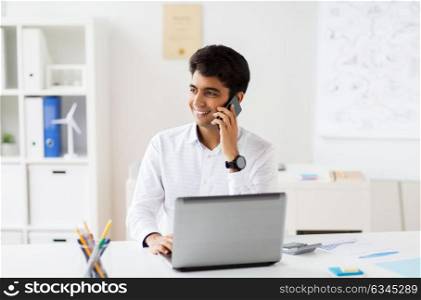 business, people and technology concept - businessman with laptop computer calling on smartphone at office. businessman calling on smartphone at office
