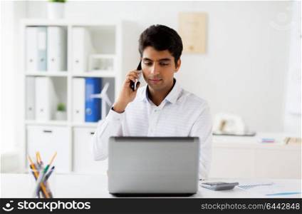 business, people and technology concept - businessman with laptop computer calling on smartphone at office. businessman calling on smartphone at office