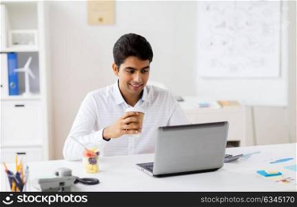 business, people and technology concept - businessman with laptop computer having meal break and drinking coffee at office. businessman with laptop drinking coffee at office