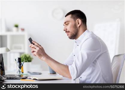 business, people and technology concept - businessman with smartphone and notebook at office. businessman with smartphone and notebook at office